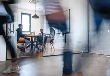 A blurry image of people in an office setting.