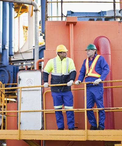 Two men in blue and yellow work vests standing on a ship.