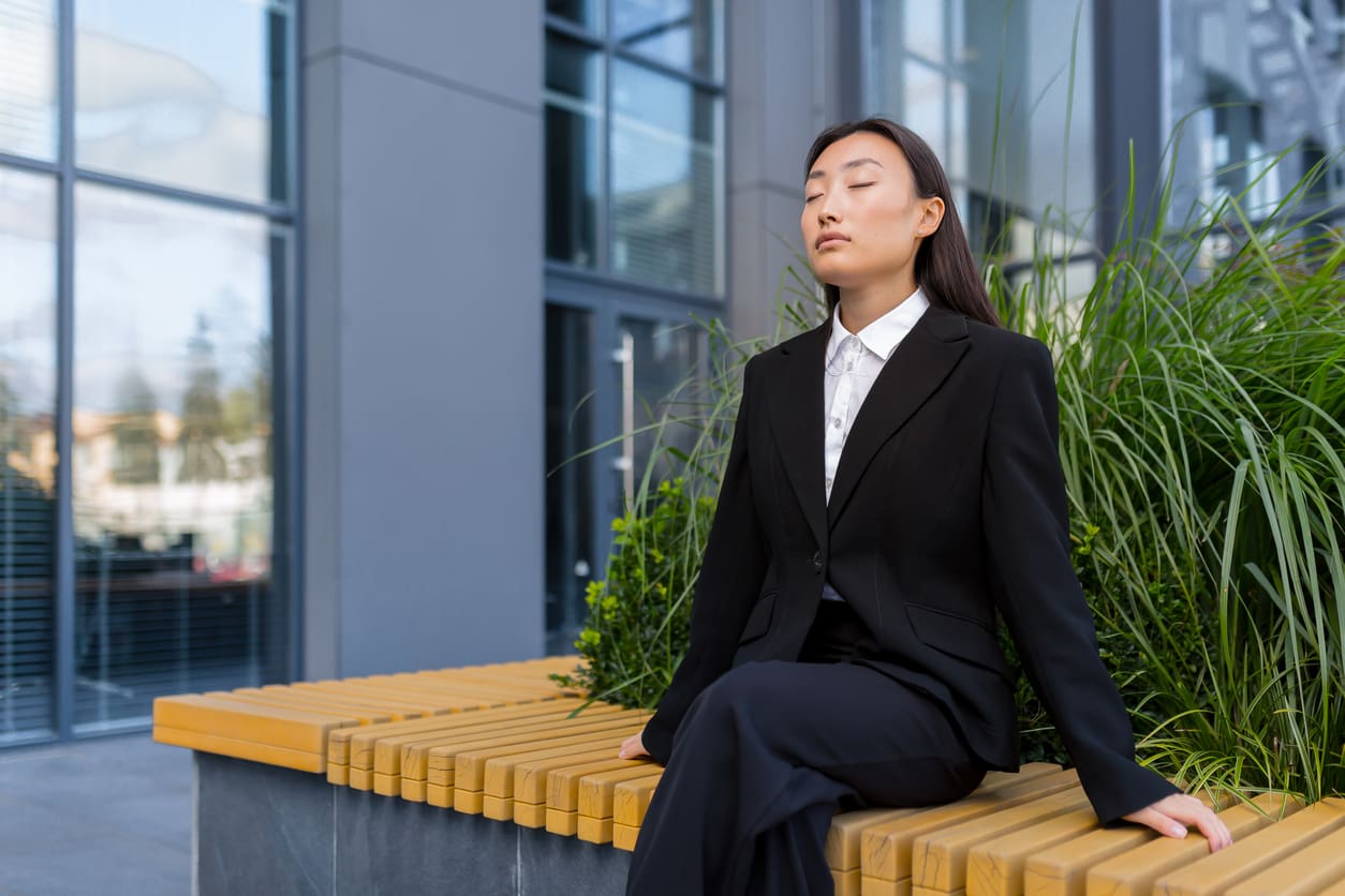 A woman in business attire sitting on top of a bench.
