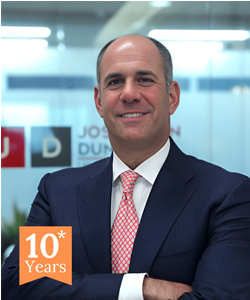 Man in suit smiling with 10 years badge.