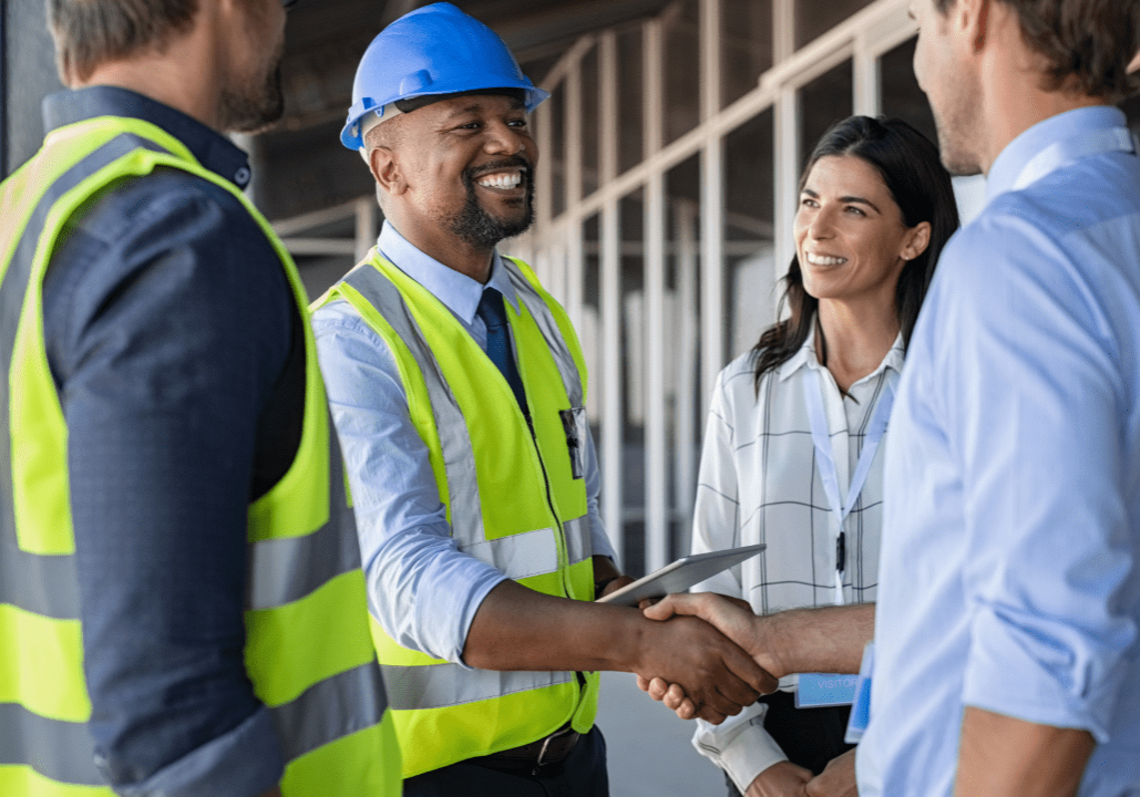 Construction workers shaking hands and smiling.